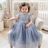 Child in a blue dress sitting on a chair in a bright room
