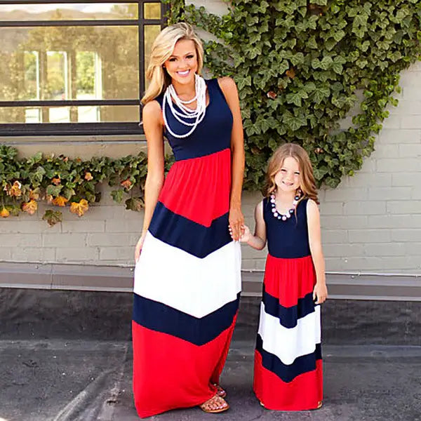 Woman and child wearing matching red, white, and blue dresses standing outdoors.